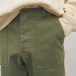 Front closeup view of khaki green pants on model wearing white sweatshirt, against white background.