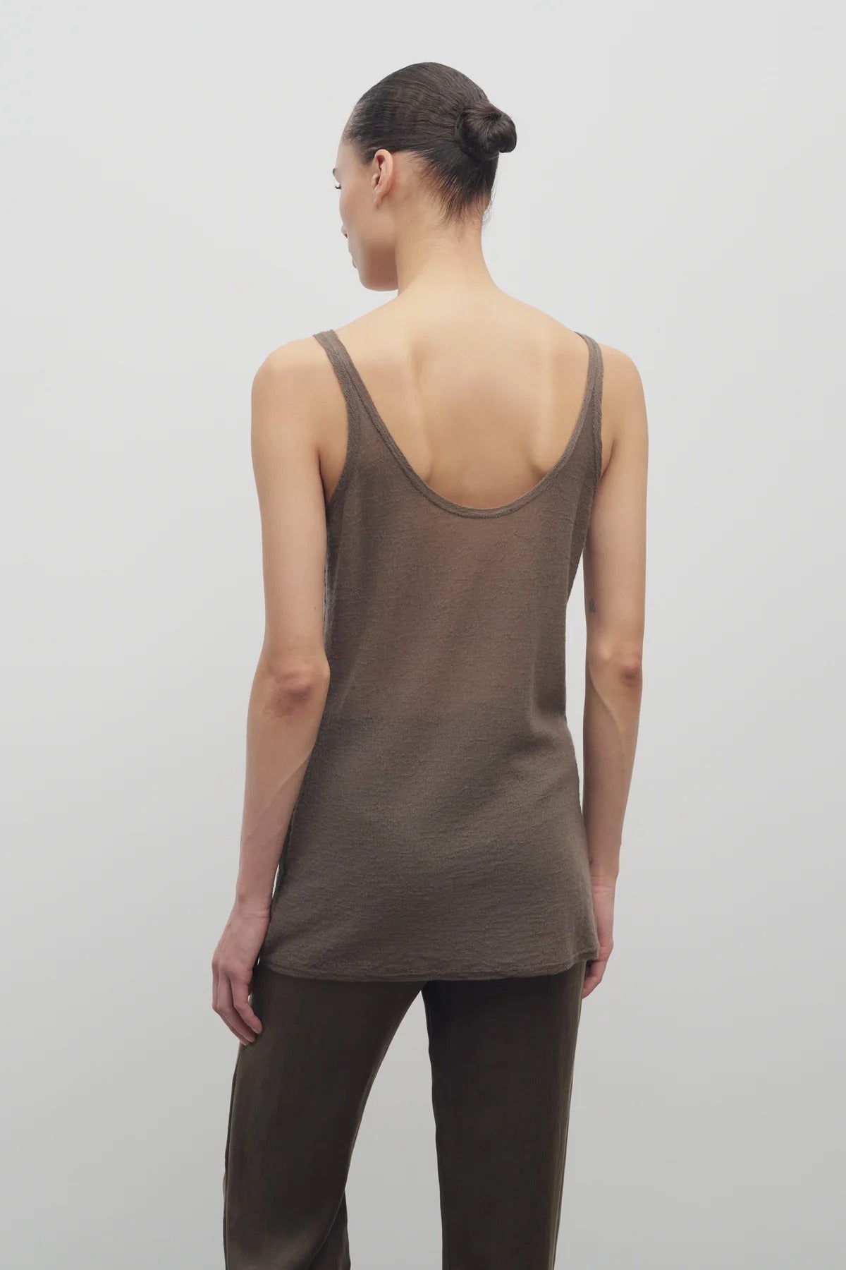 Back view of khaki kazu top on model wearing khaki pants, against a white background