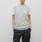 A model with dark brown hair is shown in the sleeveless knit top and navy trousers with frontside viewpoint on white backdrop
