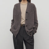 Front view of taupe laleh cardigan on model wearing beige top and charcoal pants, against a white background.