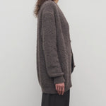 Side view of taupe laleh cardigan on model wearing charcoal pants, against a white background.