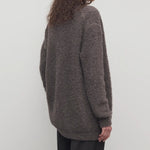 Back view of taupe laleh cardigan on model wearing charcoal pants, against a white background.