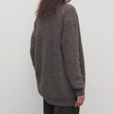 Back view of taupe laleh cardigan on model wearing charcoal pants, against a white background.