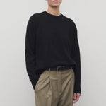 Front view of black leilani top on model wearing khaki pants with black belt, against white background.