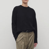Front view of black leilani top on model wearing khaki pants with black belt, against white background.