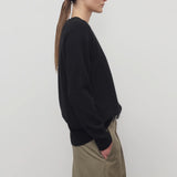 Side view of black leilani top on model wearing khaki pants, against a white background.
