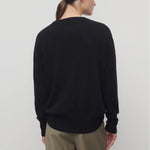 Back view of black leilani top on model wearing khaki pants, against a white background.