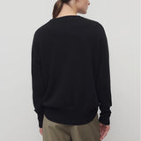Back view of black leilani top on model wearing khaki pants, against a white background.