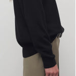 Side closeup view of black leilani top on model wearing khaki pants, against a white background.