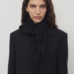 Front view of black Leomine scarf on model wearing black coat, against a white background.