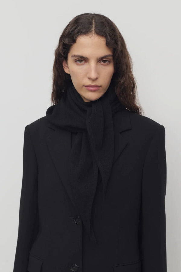 Front view of black Leomine scarf on model wearing black coat, against a white background.