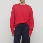 Front view of red leora sweatshirt on model wearing navy pants, against a white background.