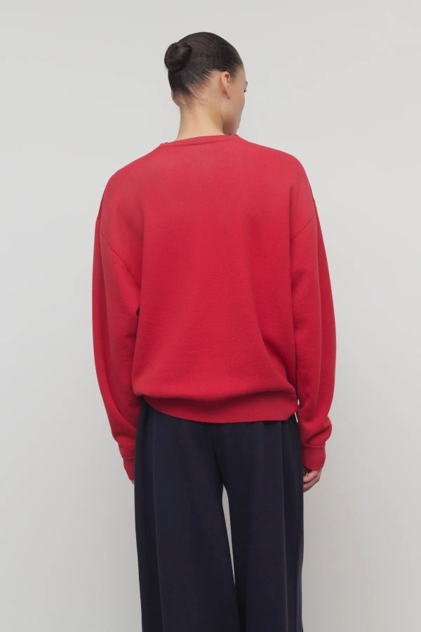 Back view of red leora sweatshirt on model wearing navy pants, against a white background.