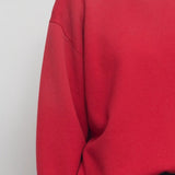 Front closeup view of red leora sweatshirt on model wearing navy pants, against a white background.