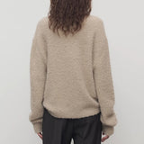 Back view of beige lethara sweater on model wearing black pants, against a white background.