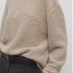 Front closeup view of beige lethara sweater on model wearing black pants, against a white background.