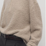 Front closeup view of beige lethara sweater on model wearing black pants, against a white background.