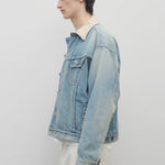 Side view of light indigo collared joret jacket on model wearing white trousers and a white t-shirt, against a white background.