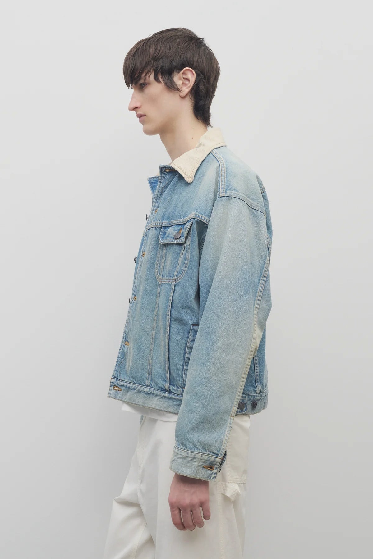 Side view of light indigo collared joret jacket on model wearing white trousers and a white t-shirt, against a white background.
