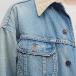 Front closeup view of light indigo collared joret jacket on model wearing white t-shirt, against a white background.