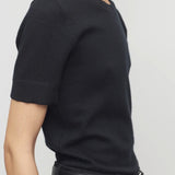 Side view of black linnea sweater on model wearing black pants and belt, against a white background.