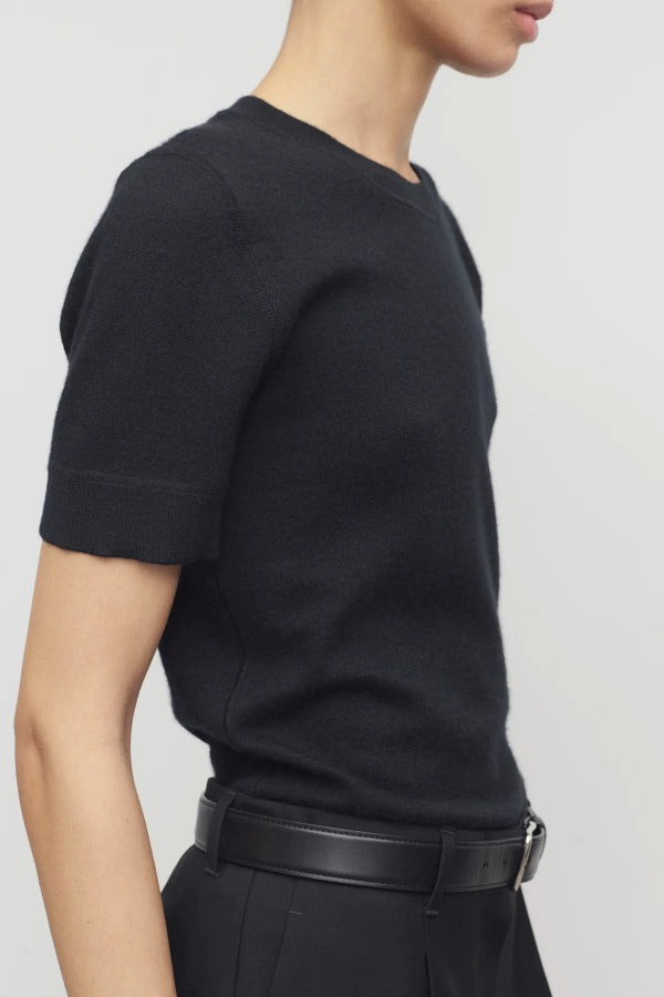 Side view of black linnea sweater on model wearing black pants and belt, against a white background.