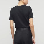 Back view of black linnea sweater on model wearing black pants and belt, against a white background.