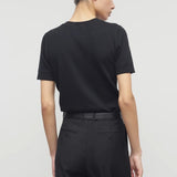 Back view of black linnea sweater on model wearing black pants and belt, against a white background.