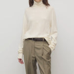 Front view of ivory lizzy top on model wearing khaki trousers and a brown belt, against a white background.