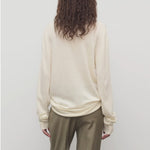 Back view of ivory lizzy top on model wearing khaki trousers, against a white background.