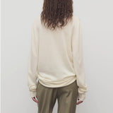 Back view of ivory lizzy top on model wearing khaki trousers, against a white background.