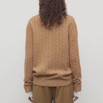 Back view of fawn loneke caridgan on model wearing camel pants, against a white background.