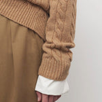 Side closeup view of fawn loneke cardigan on model wearing camel pants, against a white background.