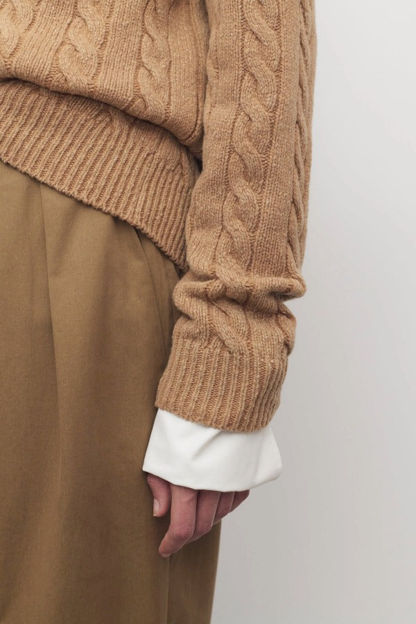 Side closeup view of fawn loneke cardigan on model wearing camel pants, against a white background.