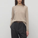 Front view of beige melange lorelei sweater on model wearing black pants and brown belt, against a white background.