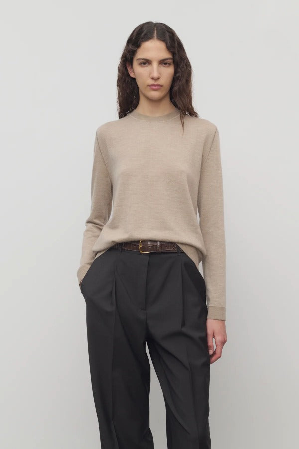 Front view of beige melange lorelei sweater on model wearing black pants and brown belt, against a white background.