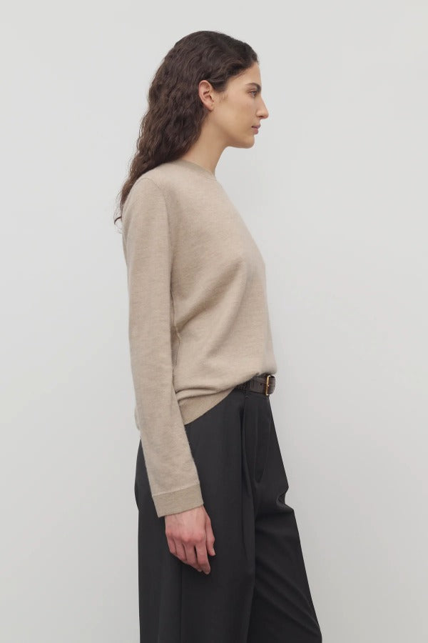 Side view of beige melange lorelei sweater on model wearing black pants and brown belt, against a white background.