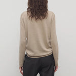 Back view of beige melange lorelei sweater on model wearing black pants, against a white background.