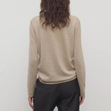 Back view of beige melange lorelei sweater on model wearing black pants, against a white background.