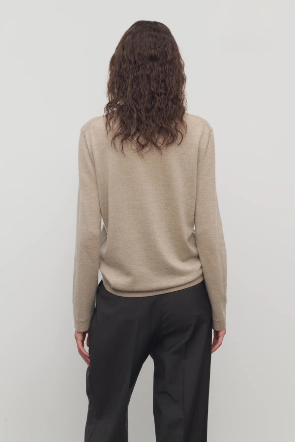 Back view of beige melange lorelei sweater on model wearing black pants, against a white background.