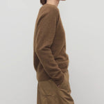 Side view of oak lorynna top on model wearing camel trousers, against a white background.