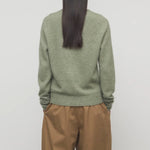 Back view of sage lorynna top on model wearing camel trousers, against a white background.