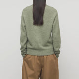Back view of sage lorynna top on model wearing camel trousers, against a white background.