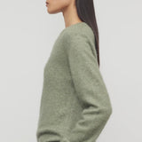 Side view of sage lorynna top on model wearing camel trousers, against a white background.