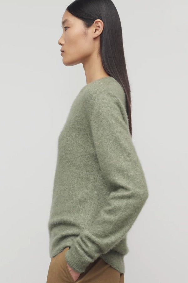 Side view of sage lorynna top on model wearing camel trousers, against a white background.