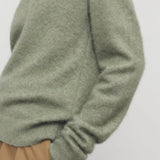 Side closeup view of sage lorynna top on model wearing camel trousers, against a white background.