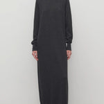 Front view of enzyme black loter dress on model wearing boots, against a white background.
