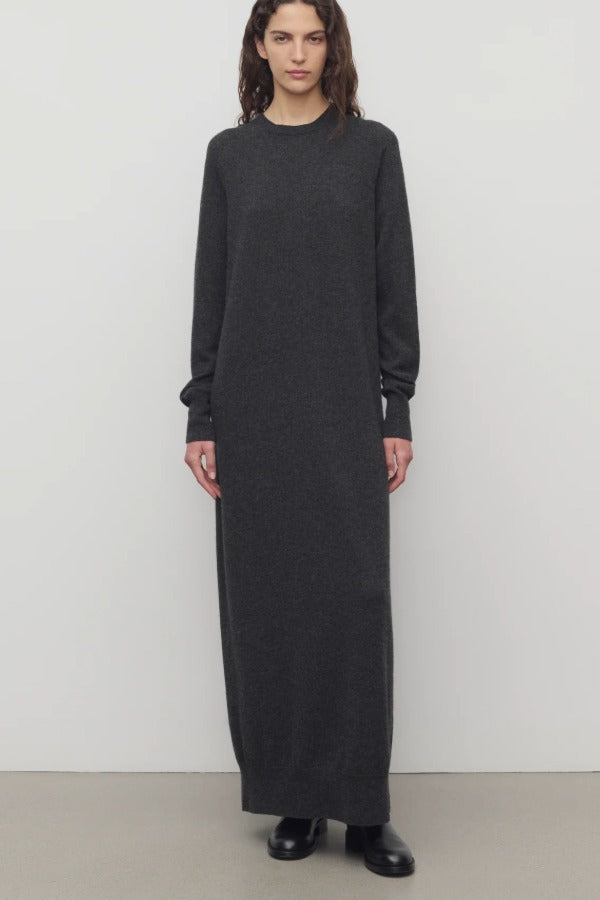 Front view of enzyme black loter dress on model wearing boots, against a white background.