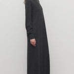 Side view of enzyme black loter dress on model wearing boots, against a white background.
