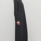 Side view of enzyme black loter dress on model wearing boots, against a white background.